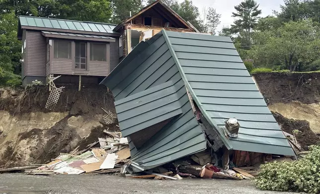 Trees and debris sit next to a damaged home after flooding in Lyndonville, Vt., Tuesday, July 30, 2024. (AP Photo/Nick Perry)