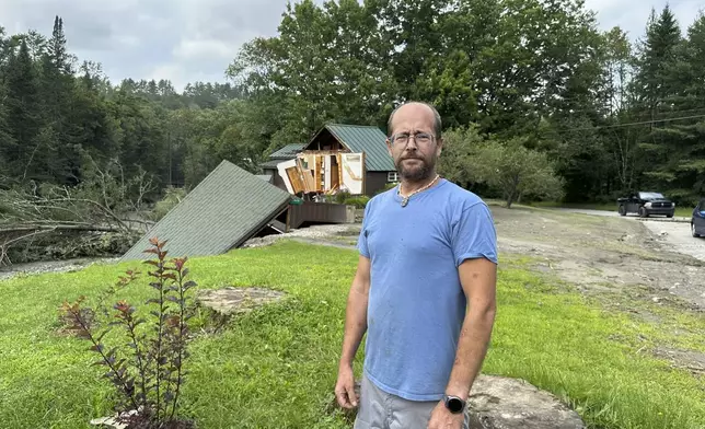 Jason Pilbin stands outside flood-damaged homes in Lyndonville, Vt., Tuesday, July 30, 2024. Pilbin helped neighbors evacuate early Tuesday morning before their house broke in half and then helped another neighbor exit her home during the heavy rains overnight, just weeks after witnessed a driver got swept away floodwaters there earlier this month. (AP Photo/Nick Perry)