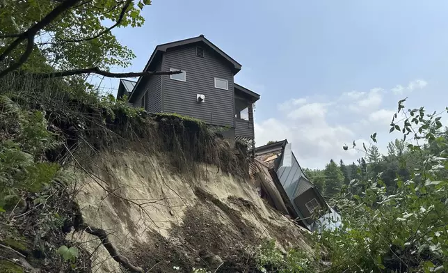 A damaged house sits on a ledge after flooding in Lyndonville, Vt., Tuesday, July 30, 2024. (AP Photo/Nick Perry)