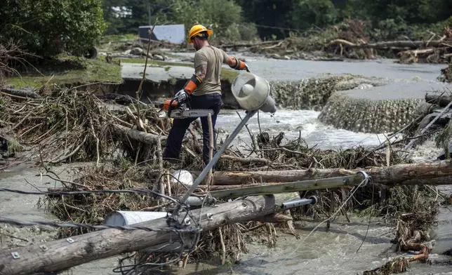 Zac Drown, of Lyndon Electric Company, clears debris amid flood damage in Lyndon, Vt., Tuesday, July 30, 2024. (AP Photo/Dmitry Belyakov)