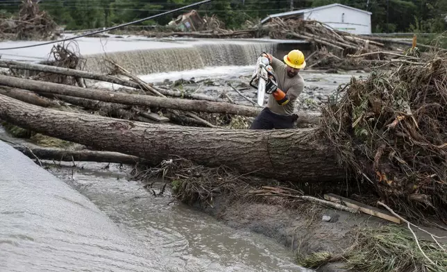 Zac Drown, of Lyndon Electric Company, clears debris amid flood damage in Lyndon, Vt., Tuesday, July 30, 2024. (AP Photo/Dmitry Belyakov)