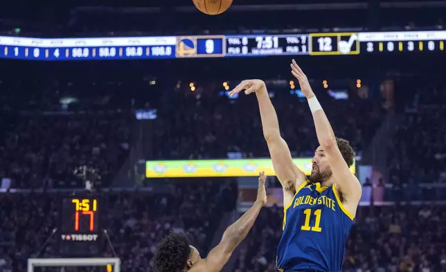 FILE - Golden State Warriors guard Klay Thompson (11) shoots a 3-point basket over Utah Jazz guard Collin Sexton, left, during the first half of an NBA basketball game April 7, 2024, in San Francisco. Thompson has been a pillar of the Warriors dynasty that won four NBA titles the past decade champions. Whether he will be part of the franchise as the team looks to rebound after missing the playoffs remains unknown. (AP Photo/Nic Coury, File)