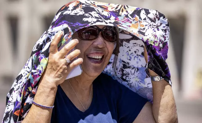 Lucita Corupuz, 80, visiting from St. Louis, covers up from the sun while visiting the University of Washington campus with family Sunday, July 7, 2024, in Seattle. An excessive heat warning — the National Weather Service's highest alert — was in effect for about 36 million people. (Ken Lambert/The Seattle Times via AP)