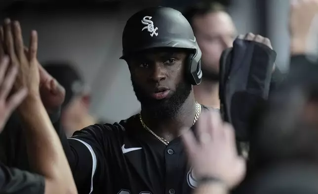 Chicago White Sox's Luis Robert Jr. celebrates in the dugout with teammates after scoring in the seventh inning of a baseball game against the Cleveland Guardians, Wednesday, July 3, 2024, in Cleveland. (AP Photo/Sue Ogrocki)