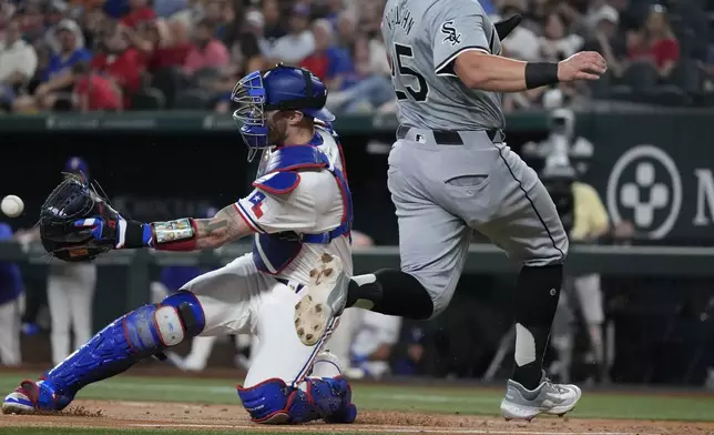 Texas Rangers catcher Jonah Heim, left, reaches for the throw home as Chicago White Sox's Andrew Vaughn (25) scores on a single by teammate Nicky Lopez during the third inning of a baseball game in Arlington, Texas, Wednesday, July 24, 2024. (AP Photo/LM Otero)