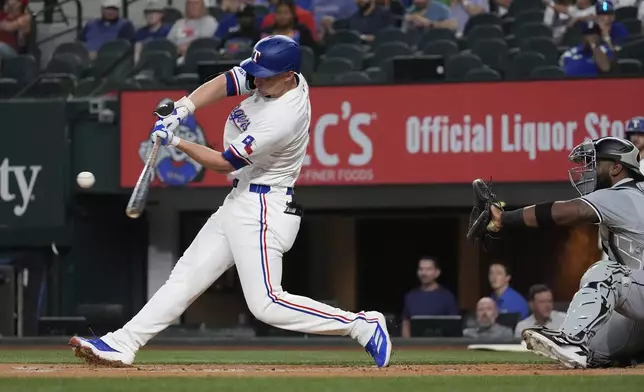 Texas Rangers' Corey Seager, right, hits a home run in front of Chicago White Sox catcher Chuckie Robinson (47) during the first inning of a baseball game in Arlington, Texas, Wednesday, July 24, 2024. (AP Photo/LM Otero)