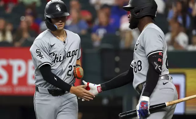 Chicago White Sox Brooks Baldwin (27) slaps hands with Luis Robert Jr. (88) after scoring against the Texas Rangers in the third inning of a baseball game Thursday, July 25, 2024, in Arlington, Texas. (AP Photo/Richard W. Rodriguez)