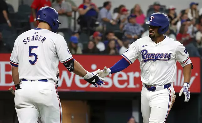 Texas Rangers' Corey Seager (5) celebrates after a solo home run by Marcus Semien, right, against the Chicago White Sox in the third inning of a baseball game Thursday, July 25, 2024, in Arlington, Texas. (AP Photo/Richard W. Rodriguez)