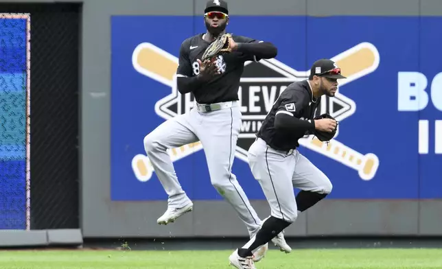 Chicago White Sox center fielder Luis Robert Jr., left, catches a fly ball off the bat of Kansas City Royals' Hunter Renfroe while dodging left fielder Tommy Pham, right, during the sixth inning of a baseball game, Sunday, July 21, 2024, in Kansas City, Mo. (AP Photo/Reed Hoffmann)