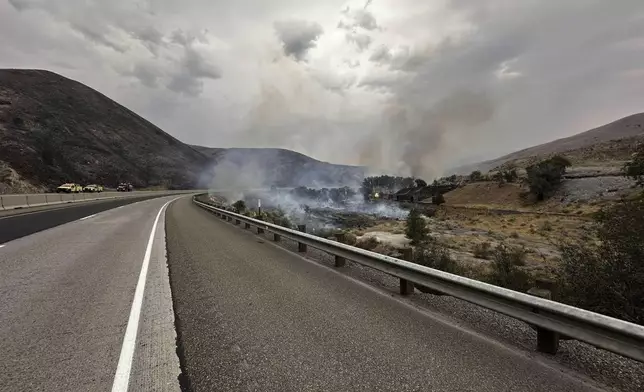 In this image provided by the U.S. Department of Agriculture Forest Service, smoke rises from the Durkee wildfire on Wednesday, July 24, 2024, by the I-84 near Lime, Ore. In eastern Oregon, evacuation orders were lifted Thursday for the city of Huntington, population 500, after a severe thunderstorm late Wednesday brought some rain and cooler temperatures to the nearly 630 square miles (1,630 square kilometers) burned by the Durkee Fire, the nation's biggest, and another nearby blaze.(Brett Brown/USDA Forest Service via AP)