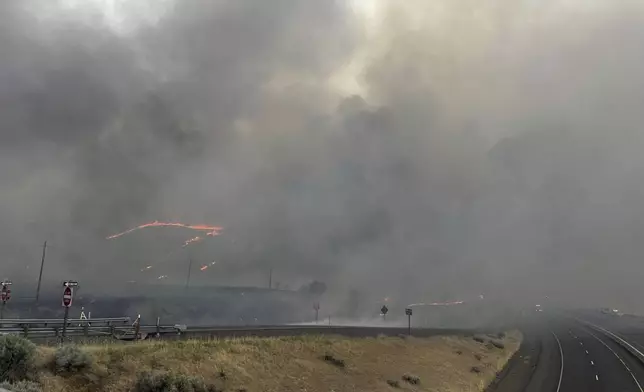 In this image provided by the U.S. Department of Agriculture Forest Service, smoke rises from the Durkee wildfire on Wednesday, July 24, 2024, at the I-84 Rye Valley exit in Oregon. In eastern Oregon, evacuation orders were lifted Thursday for the city of Huntington, population 500, after a severe thunderstorm late Wednesday brought some rain and cooler temperatures to the nearly 630 square miles (1,630 square kilometers) burned by the Durkee Fire, the nation's biggest, and another nearby blaze. (Brett Brown/USDA Forest Service via AP)