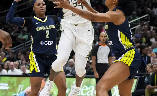 Seattle Storm guard Jewell Loyd (24) jumps up for a basket against Dallas Wings guard Odyssey Sims (2) and forward Monique Billings, right, during the first half of a WNBA basketball game, Monday, July 1, 2024, in Seattle. (AP Photo/Lindsey Wasson)