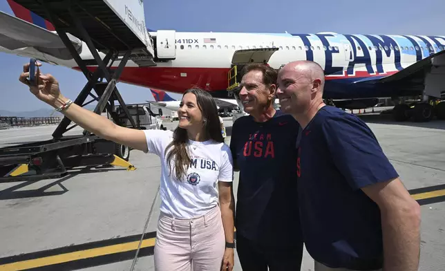 Salt Lake City Mayor Erin Mendenhall, left, Fraser Bullock and Utah Gov. Spencer Cox take a selfie near the plane as Utah's Olympic delegation boards Delta Flight 2034, Monday, July 22, 2024, bound for Paris from the Salt Lake International Airport. (Scott G Winterton/The Deseret News via AP)