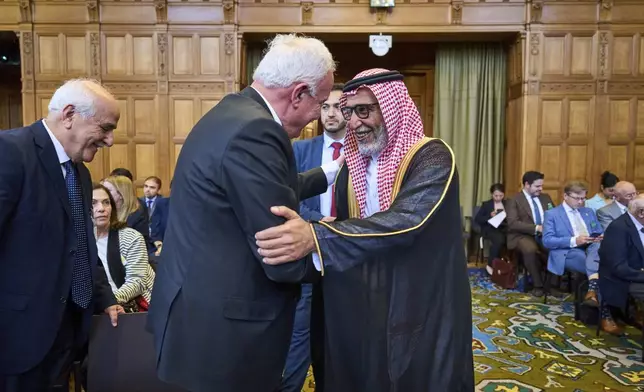 Palestinian foreign policy advisor Riad Malki meets one one the Israeli team members before judges enter the International Court of Justice, or World Court, in The Hague, Netherlands, Friday July 19, 2024, where the United Nations top court is delivering a nonbinding advisory opinion Friday on the legality of Israel's 57-year occupation of lands sought for a Palestinian state, a ruling that could have more effect on international opinion than it will on Israeli policies. (AP Photo/Phil Nijhuis)