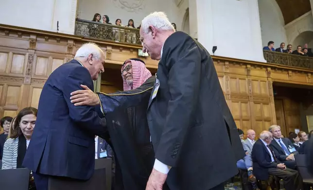 Palestinian foreign policy advisor Riad Malki meets one one the Israeli team members before judges enter the International Court of Justice, or World Court, in The Hague, Netherlands, Friday July 19, 2024, where the United Nations top court is delivering a nonbinding advisory opinion Friday on the legality of Israel's 57-year occupation of lands sought for a Palestinian state, a ruling that could have more effect on international opinion than it will on Israeli policies. (AP Photo/Phil Nijhuis)