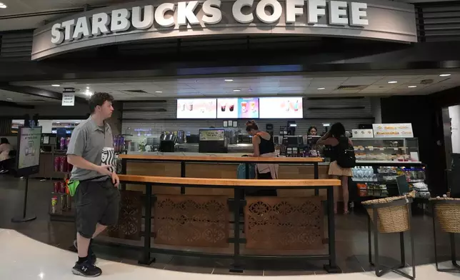 A patron walks out of a Starbucks at Phoenix Sky Harbor International Airport Friday, July 19, 2024, in Phoenix. A global technology outage grounded flights, knocked banks offline and media outlets off air after a faulty software update disrupted companies and services around the world and highlighted their dependence on just a handful of providers (AP Photo/Ross D. Franklin)