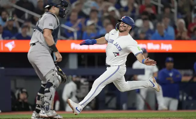 Toronto Blue Jays' Spencer Horwitz, right, scores on a single by teammate Justin Turner during third-inning baseball game action against the New York Yankees in Toronto, Sunday, June 30, 2024. (Frank Gunn/The Canadian Press via AP)