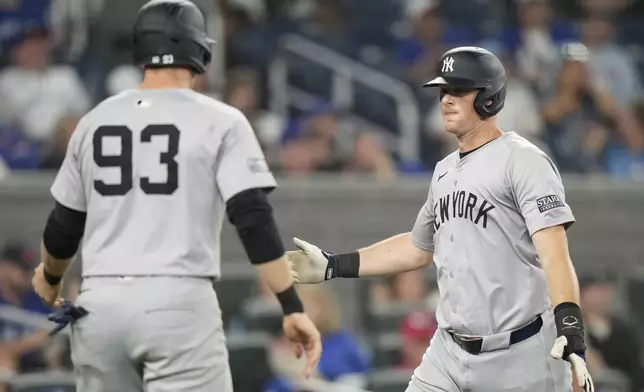 New York Yankees third base DJ LeMahieu, right, and teammate Ben Rice (93) celebrate after scoring on a double by Trent Grisham during fifth-inning baseball game action against the Toronto Blue Jays in Toronto, Sunday, June 30, 2024. (Frank Gunn/The Canadian Press via AP)