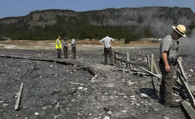 In this photo released by the National Park Service, park staff assess the damage to Biscuit Basin boardwalks after a hydrothermal explosion at Biscuit Basin in Yellowstone National Park, Wyo., Tuesday, July 23, 2024. (National Park Service via AP)