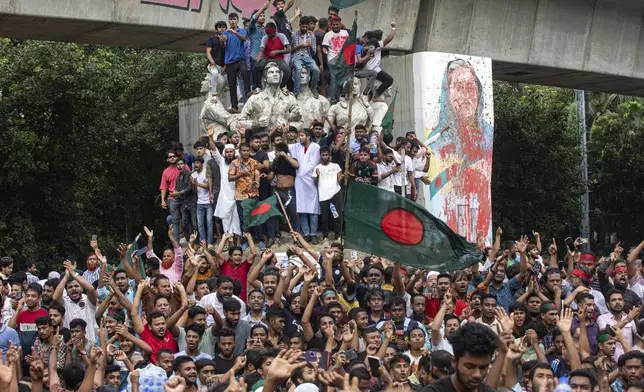 Protesters climb a public monument as they celebrate after getting the news of Prime Minister Sheikh Hasina's resignation, in Dhaka, Bangladesh, Monday, Aug. 5, 2024. (AP Photo/Rajib Dhar)