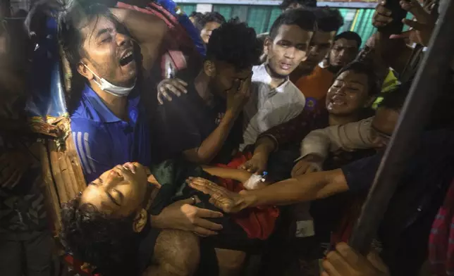 People cry as the dead body of a man, who was killed during the anti-government protests in Bangladesh, is brought to a hospital in Dhaka, Bangladesh, Sunday, Aug. 4, 2024. (AP Photo/Rajib Dhar)