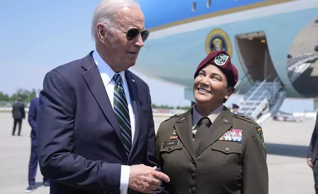 President Joe Biden talks with reporters Tuesday, Aug. 13, 2024, at Louis Armstrong International Airport in New Orleans, as Army Reserve Maj. Gen. Andreé Carter listens. (AP Photo/Mark Schiefelbein)