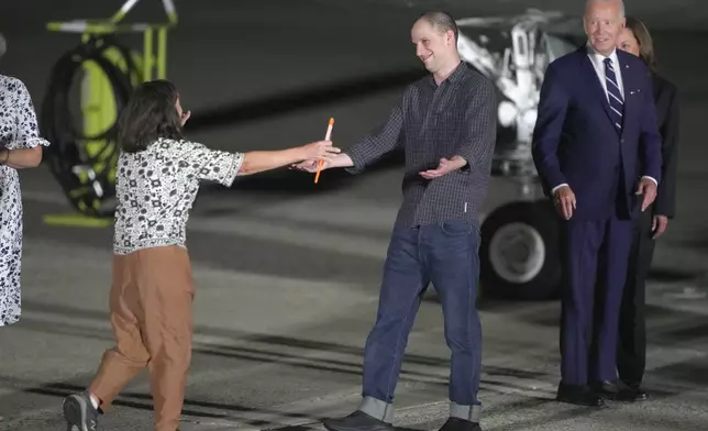 Reporter Evan Gershkovich is greeted on the tarmac by his mother, Ella Milman, as President Joe Biden and Kamala Harris look on at Andrews Air Force Base, Md., following his release as part of a 24-person prisoner swap between Russia and the United States, Thursday, Aug. 1, 2024. (AP Photo/Manuel Balce Ceneta)