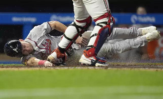 Atlanta Braves' Jarred Kelenic, left, touches home plate to score off a fielder's choice hit by teammate Matt Olson during the 10th inning of a baseball game against the Minnesota Twins, Tuesday, Aug. 27, 2024, in Minneapolis. (AP Photo/Abbie Parr)