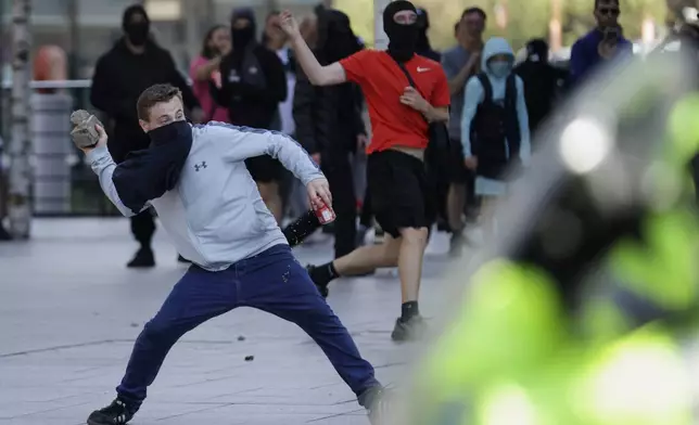 A demonstrator throws a brick during a protest in Liverpool, England, on Saturday, Aug. 3, 2024, following Monday's stabbing attacks in Southport, in which three young children were killed. (James Speakman/PA via AP)