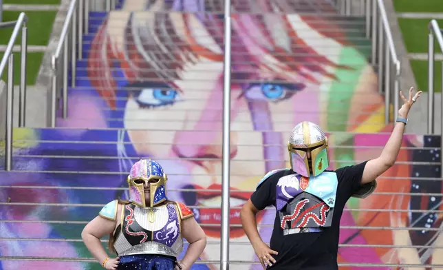 Kristina Broclebanl, left and Max Avatar Barnett who are Taylor Swift fans pose by a portrait of Swift painted on a stairway at Wembley Stadium in London, Wednesday, Aug. 14, 2024, ahead of a series of Taylor Swift concerts starting Thursday. (AP Photo/Alastair Grant)