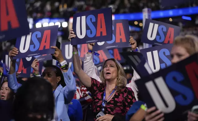 Delegates hold signs during the Democratic National Convention Tuesday, Aug. 20, 2024, in Chicago. (AP Photo/Erin Hooley)