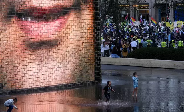 Children play in the water as protesters march prior to the start of the Democratic National Convention Sunday, Aug. 18, 2024, in Chicago.(AP Photo/Julio Cortez)