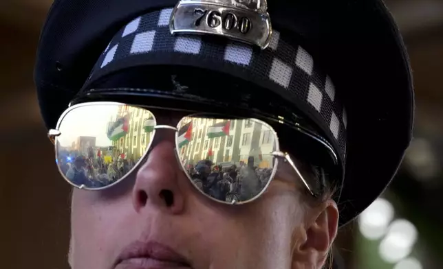 A police officer watches protesters march during a demonstration outside the Democratic National Convention Wednesday, Aug. 21, 2024, in Chicago. (AP Photo/Alex Brandon)