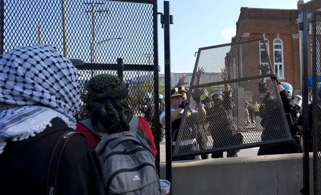 Police replace a piece of fence knocked down by protesters surrounding the United Center at the Democratic National Convention after a march Monday, Aug. 19, 2024, in Chicago. (AP Photo/Frank Franklin II)