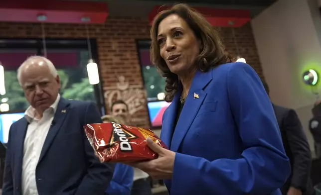 Democratic presidential nominee Vice President Kamala Harris holds a bag of Doritos chips as Democratic vice presidential nominee Minnesota Gov. Tim Walz looks on at Sheetz convenience store during a campaign stop, Sunday, Aug. 18, 2024, in Coralpolis, Pa. (AP Photo/Julia Nikhinson)