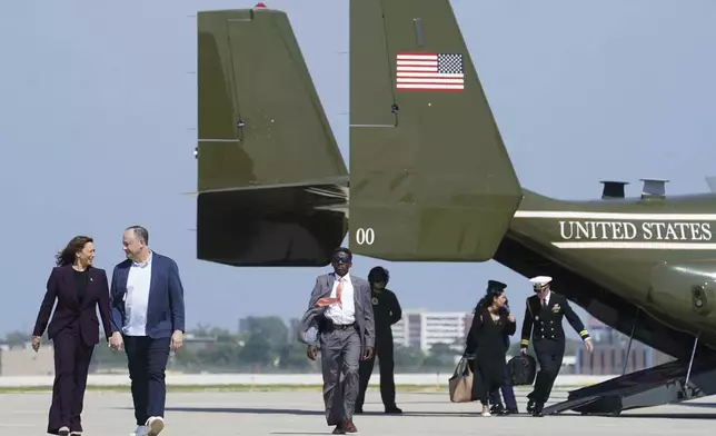 Democratic presidential nominee Vice President Kamala Harris, from left, and second gentleman Doug Emhoff walk from Marine Two to board Air Force Two, Friday, Aug. 23, 2024, at Chicago O'Hare International Airport in Chicago, en route to Washington. (Kevin Lamarque/Pool via AP)