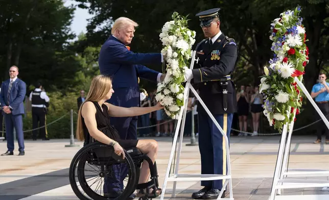 Former U.S. Marine Corps Cpl. Kelsee Lainhart left, and Republican presidential nominee former President Donald Trump place a wreath at the Tomb of the Unknown Solider in honor of the 13 service members killed at Abbey Gate, at Arlington National Cemetery, Monday, Aug. 26, 2024, in Arlington, Va. (AP Photo/Alex Brandon)