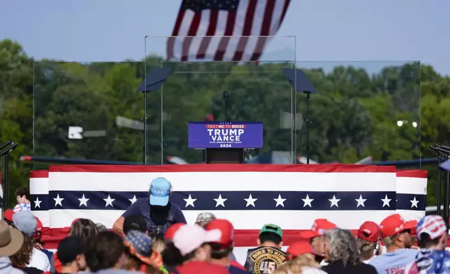 An outdoor stage is set encased with bulletproof glass as supporters arrive to hear Republican presidential nominee former President Donald Trump speak at a rally, Wednesday, Aug. 21, 2024, in Asheboro, N.C. Trump is holding his first outdoor rally since narrowly surviving an attempted assassination when a a gunman opened fire in Pennsylvania last month. (AP Photo/Julia Nikhinson)