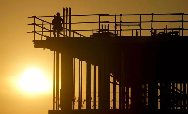 Construction workers start their day as the sun rises on the new Republic Airlines headquarters building in Carmel, Ind., Tuesday, Aug. 27, 2024. (AP Photo/Michael Conroy)