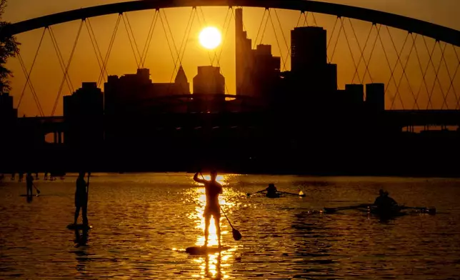 People paddle on the Main river in Frankfurt, Germany, as the sun sets on Wednesday, Aug. 28, 2024. (AP Photo/Michael Probst)