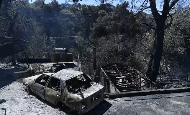 A charred vehicle and homes lie in ruins after a wildfire swept through the suburb of Nea Penteli in Athens, Tuesday, Aug. 13, 2024. (AP Photo/Michael Varaklas)