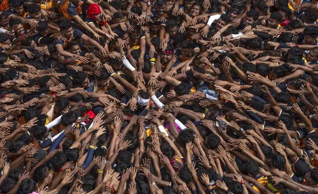 Revelers pay respect before forming human pyramids to reach an overhanging earthen pot while celebrating Hindu festival Janmashtami, the festival that marks the birth of Hindu God Krishna, in Mumbai, India, Tuesday, Aug. 27, 2024.(AP Photo/Rafiq Maqbool)