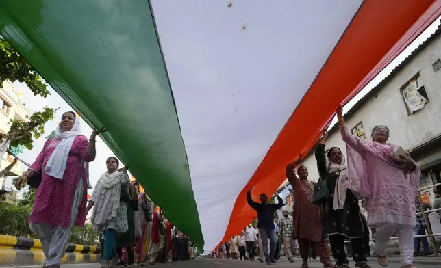 People carry a giant Indian flag during a march ahead of Independence Day in Ahmedabad, India, Tuesday, Aug. 13, 2024. (AP Photo/Ajit Solanki)