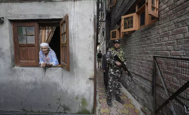 An elderly Kashmiri woman looks on as a paramilitary soldier guard during the door-to -door election campaigning by Bharatiya Janata Party (BJP) candidate ahead of the Jammu and Kashmir state assembly elections, in Srinagar, Indian controlled Kashmir,Thursday, Aug. 29, 2024. (AP Photo/Mukhtar Khan)