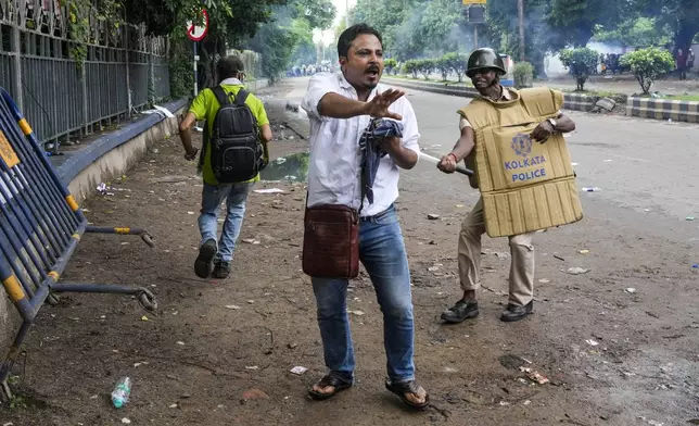 A policeman hits a protester, protesting against the rape and murder of a resident doctor at a government hospital earlier this month, in Kolkata, India, Tuesday, Aug. 27, 2024. (AP Photo/Bikas Das)