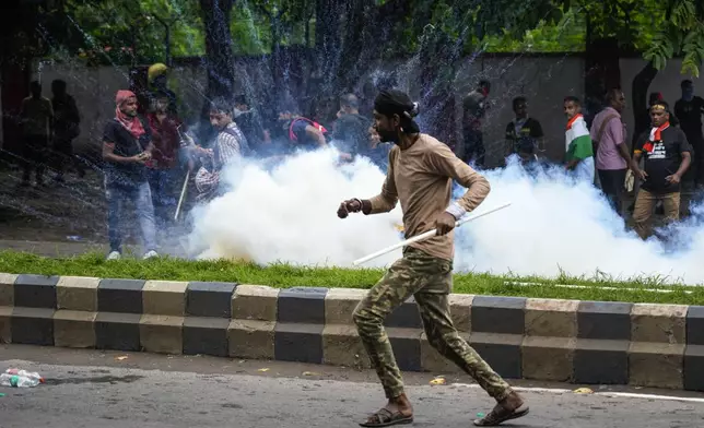 Protestors against the rape and murder of a resident doctor at a government hospital earlier this month, runs as police fire tear gas, in Kolkata, India, Tuesday, Aug. 27, 2024. (AP Photo/Bikas Das)