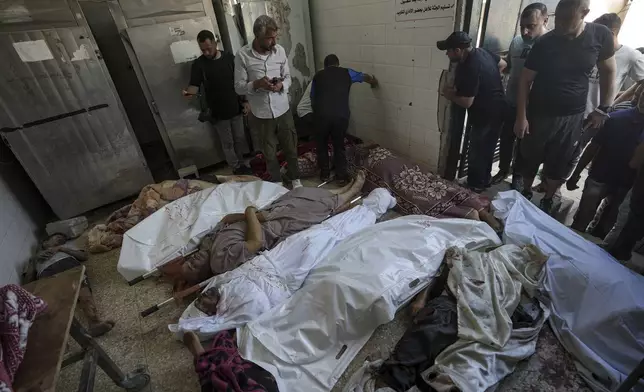 Palestinians check the bodies of their relatives killed in the Israeli bombardment of the Gaza Strip, at a hospital morgue in Deir al-Balah, Tuesday, Aug. 27, 2024. (AP Photo/Abdel Kareem Hana)