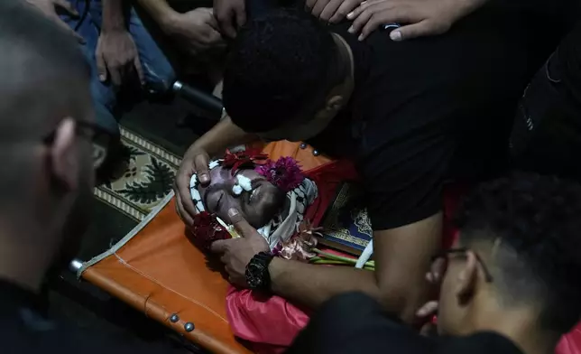 Mourners pay their last respects to Mohammad Sarsour, 18, who was killed during clashes with the Israeli army amid an overnight operation to demolish two apartments in Ramallah, during his funeral in the West Bank refugee camp of Amari in Ramallah, Tuesday, Aug. 13, 2024. (AP Photo/Nasser Nasser)