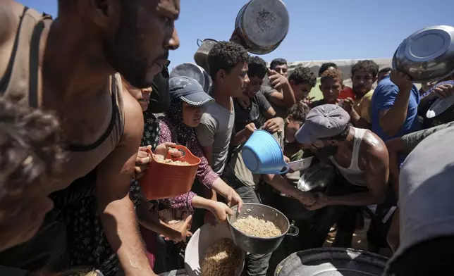 Displaced Palestinians gather for food distribution in Deir al Balah, central Gaza Strip, Friday, Aug. 23, 2024. (AP Photo/Abdel Kareem Hana)