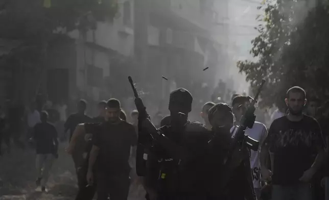 Gunmen fire their weapons during the funeral of three Palestinians killed by an Israeli airstrike in the occupied West Bank refugee camp of Tulkarem, Thursday, Aug. 22, 2024. The Palestinian Health Ministry says three people have been killed in an Israeli strike in the occupied West Bank. (AP Photo/Majdi Mohammed)